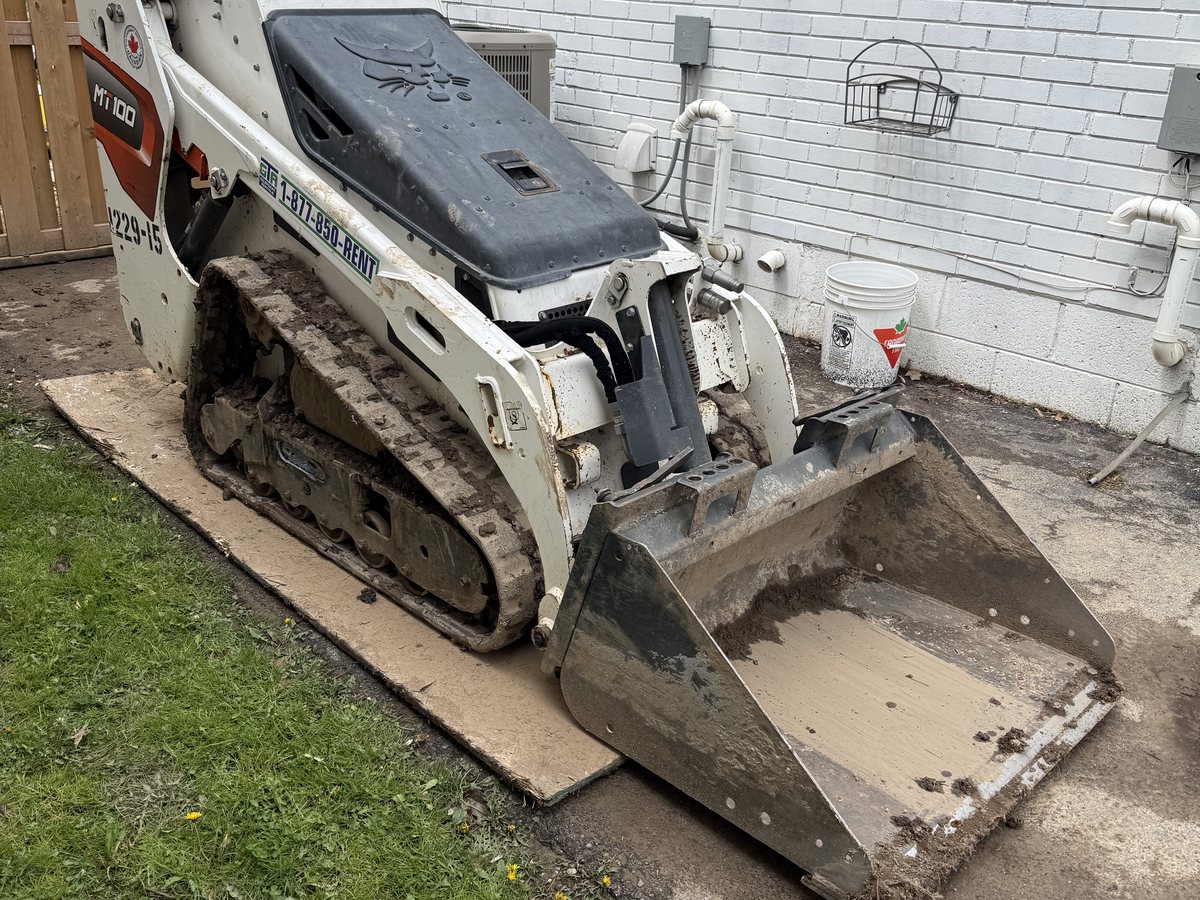 Bobcat MT100 mini track loader working in a narrow backyard